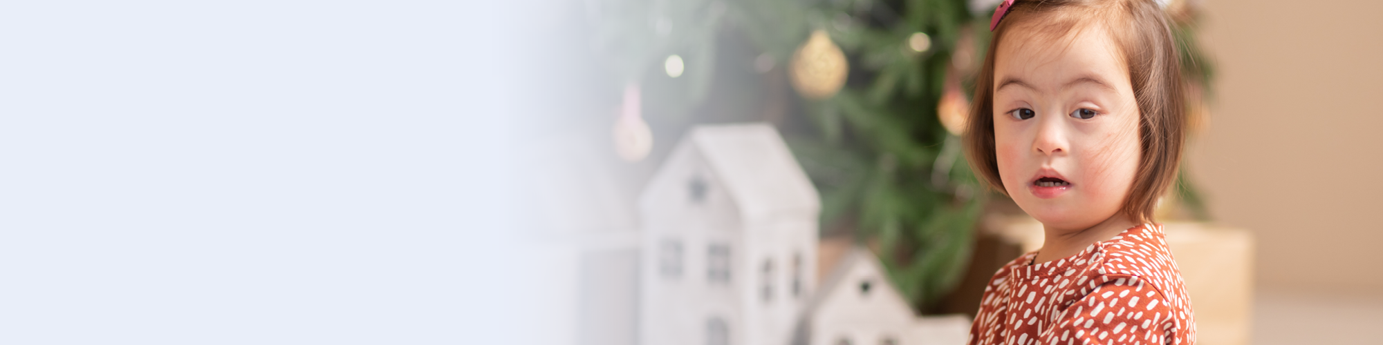 Ein kleines Kind in der Nahaufnahme. In Hintergrund ist ein Weihnachtsbaum zu erkennen.