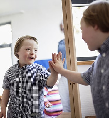 Ein Junge mit Down-Syndrom schaut in den Spiegel.