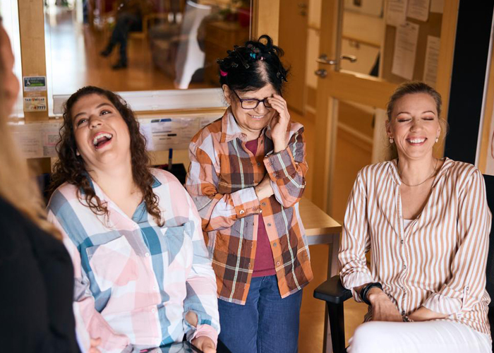 Eine inklusive Gruppe aus drei Frauen. Alle drei lachen herzlich.