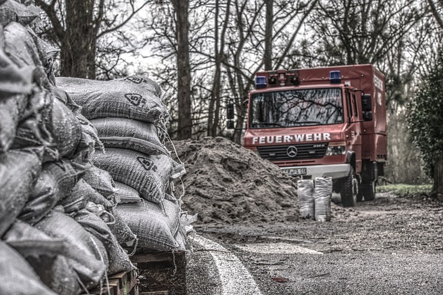 Katastrophenschutz bei Hochwasser: Im Bild sind Sandsäcke und eine Feuerwehr zu sehen.