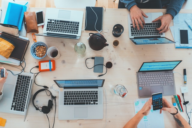 Blick von oben auf einen Tisch voller Laptops und Handys.