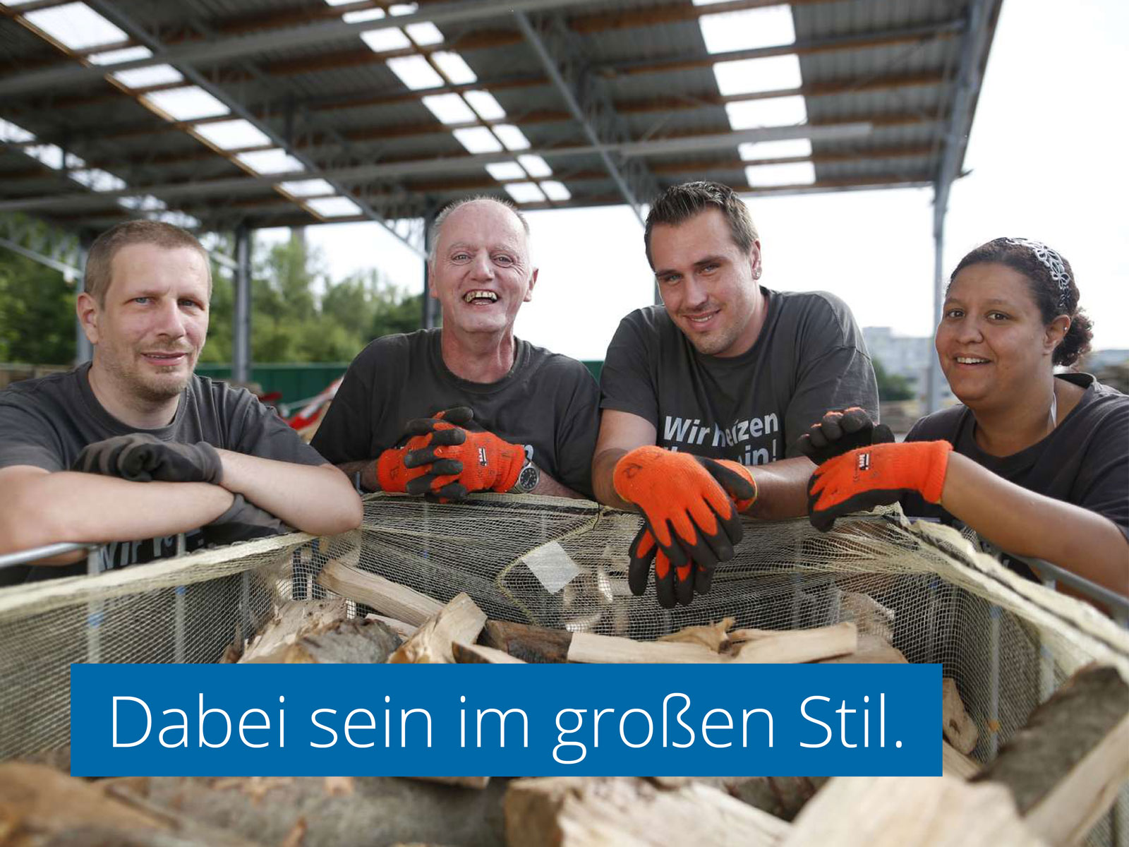 Drei Männer und eine Frau in Arbeitskleidung lehnen sich lachend über die Kante eines Containers mit Holz. In das Foto ist eine Schrift eingelassen: "Dabei sein in großem Stil."