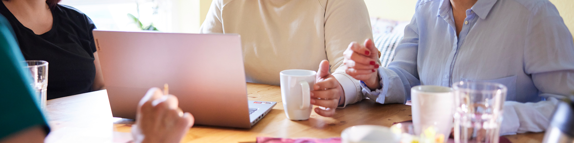 Drei Personen vor einem Notebook in der Nahaufnahme.