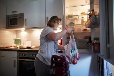Alltagshelfer Eine Frau räumt ihren Einkauf in den Kühlschrank