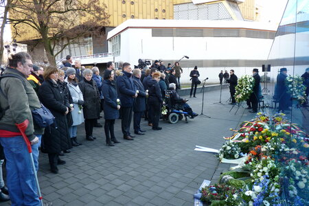 Das Bild zeigt viele Menschen, Kränze mit Blumen vor der blauen Wand der Gedenkstätte in der Berliner Tiergartenstraße.