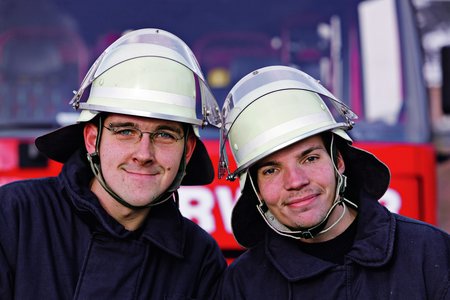 Zwei Männer mit Feuerwehrhelmen.