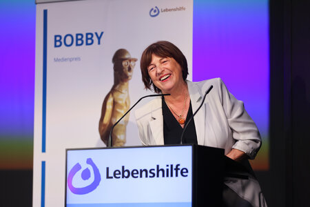 Bundesvorsitzende Ulla Schmidt hält die Laudatio auf die BOBBY-Preisträger*innen Shari und André Dietz.