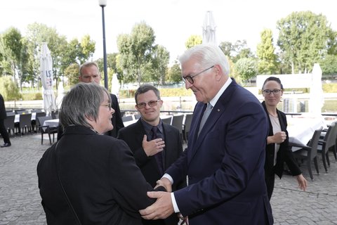 Ramona Günther, Selbstvertreterin mit Behinderung aus dem Bundesvorstand der Lebenshilfe, und Moderator Sebastian Urbanski, Schauspieler mit Down-Syndrom aus Berlin, begrüßen Bundespräsident Frank-Walter Steinmeier vor dem Café Auster.