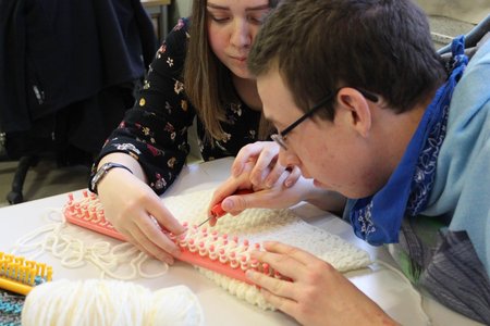 Frau hilft Mann beim Stricken