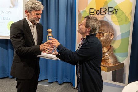 Sebastian Urbanski (rechts), Bundesvorstandsmitglied der Lebenshilfe, überreicht Florian Jaenicke den BOBBY-Preis.