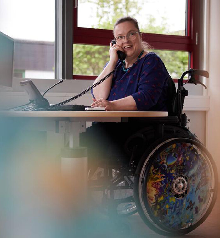 Mitarbeitende mit Behinderung Eine junge Frau mit Beeinträchtigung an ihrem inklusiven Arbeitsplatz.