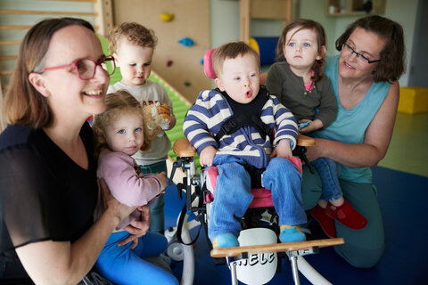 Eine Gruppe aus Kindern ist auf diesem Bild zu sehen. Eines der Kinder hat eine sogenannte geistige Behinderung und sitzt in einem Rollstuhl.