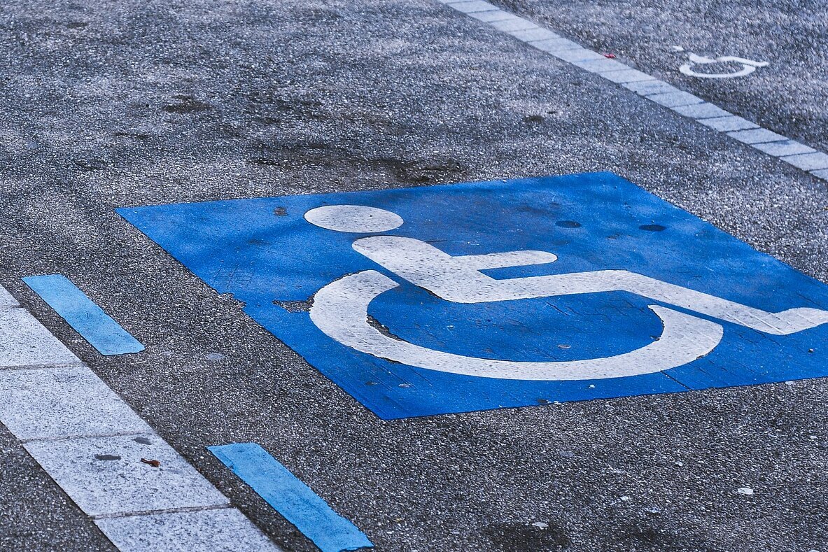 Eine Straße mit einem großen Symbol, das einen Parkplatz für Menschen mit Behinderung kennzeichnet.
