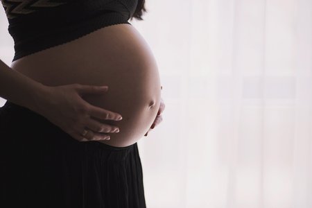 Schwangere Frau befühlt ihren Bauch 