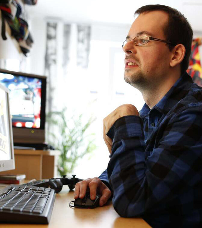 Online-Umfrage zur Bezeichnung "geistige Behinderung" Ein junger Mann sitzt vor einem Computerbildschirm und liest.