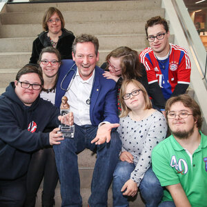 Das Bild zeigt Dr. Eckart von Hirschhausen mit früheren BOBBY-Preisträgerinnen und -Preisträgern auf einer Treppe sitzend.