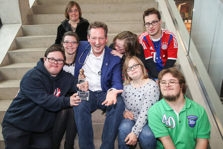 Das Bild zeigt Dr. Eckart von Hirschhausen mit früheren BOBBY-Preisträgerinnen und -Preisträgern auf einer Treppe sitzend.