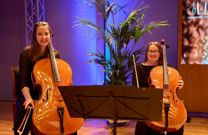 Zwei Musikerinnern sitzen mit ihren Musikinstrumenten auf einer Bühne.