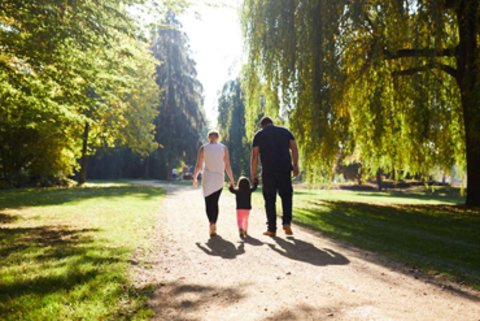 Eine junge Familie spaziert durch einen Park.