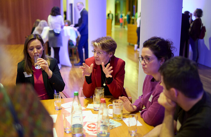 Mehrere Menschen sitzen an einem Tisch und unterhalten sich.